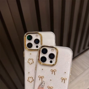 Detail of glitter iPhone case with golden bow and floral metal accents in white finish