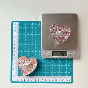 Macro di due supporti per telefono in resina a forma di cuore con glitter rosa e logo