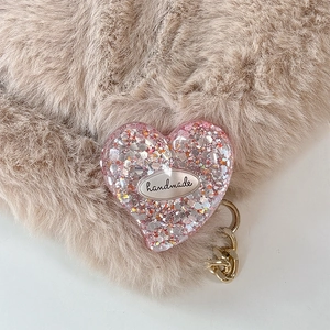 Close-up of pink glitter heart phone grip featuring a handmade label on plush background