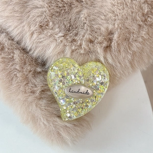 Close-up of yellow glitter heart phone grip with an engraved handmade metal tag