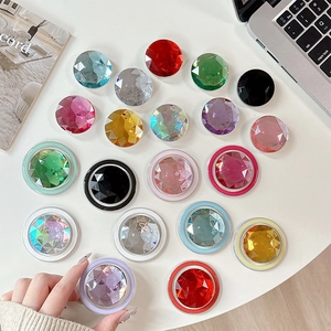 Colorful rhinestone expandable phone socket grip in various gemstone colors on white desk