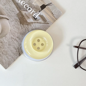 Close-up of a creative yellow button phone socket stand on a minimalist white desk