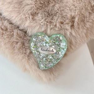 Macro shot of heart-shaped glitter phone socket with handmade silver tag on faux fur
