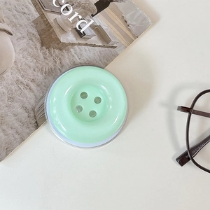 Detail shot of a mint green button-shaped collapsible phone socket on a desk