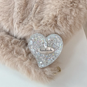Macro detail of heart-shaped glitter phone grip with a silver handmade metal plate