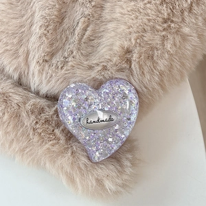 Macro view of purple glitter heart phone grip with handmade engraving on faux fur
