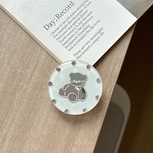 Macro detail of rhinestone-studded round phone grip featuring a cute bear icon