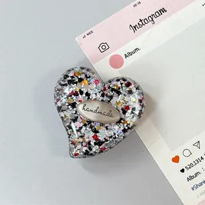 Dettaglio dell'impugnatura per telefono a cuore con glitter e targhetta fatta a mano