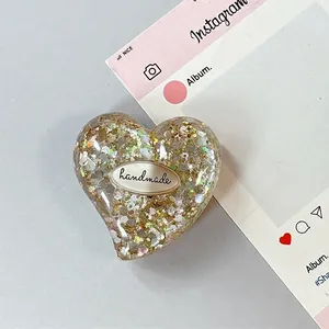 Dettaglio del Griptok a forma di cuore con paillettes luccicanti ed etichetta fatta a mano