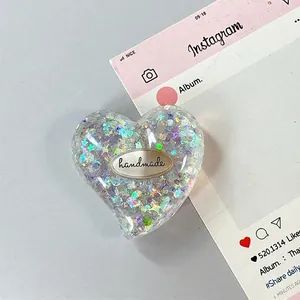Dettaglio del supporto per telefono a forma di cuore con glitter e targhetta handmade