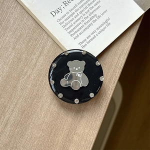 Detail of a round black phone grip with a silver bear mirror and sparkling rhinestones
