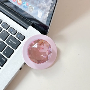 Close-up of pink diamond phone grip holder with faceted crystal on laptop desk
