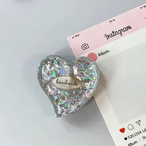 Dettaglio del supporto per telefono glitterato a cuore con emblema fatto a mano