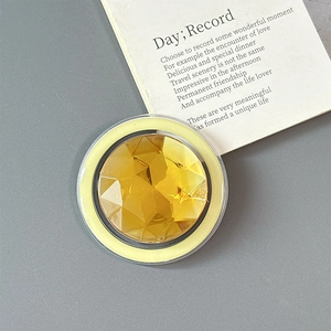 Macro shot of a luxury round amber gemstone magnetic phone ring holder on gray background