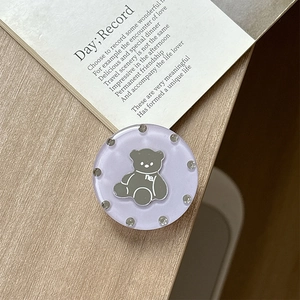 Macro view of purple acrylic bear phone grip with rhinestones on a wooden desk