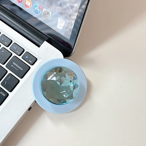 Macro detail of a light blue crystal phone grip on a laptop, showing diamond-cut facets