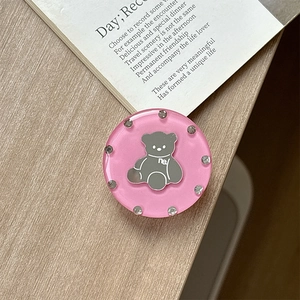 Close-up of pink round phone grip with bear pattern and shiny rhinestone border