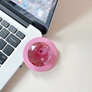 Detail view of pink crystal gemstone collapsible phone grip on a silver laptop surface