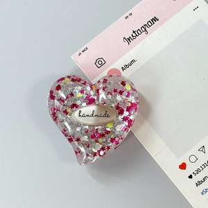 Dettaglio del supporto per telefono a cuore in resina con glitter a stelle e tag