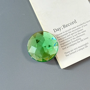 Close-up of green multifaceted diamond cut phone grip on a minimalist grey background