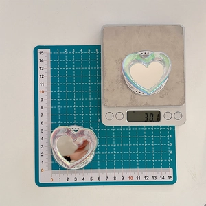 Detailed view of the 30g heart-shaped holographic phone grip on a measurement scale