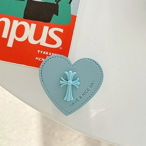 Detail der hellblauen herzförmigen Leder-Handyhalterung mit geprägtem Kreuz und Text