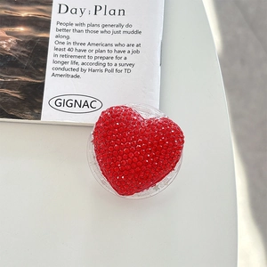 Macro shot of heart-shaped phone grip with red rhinestones on a white table