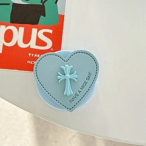 Nahaufnahme des herzförmigen blauen Leder-MagSafe-Halters mit Kreuzdetail und Naht