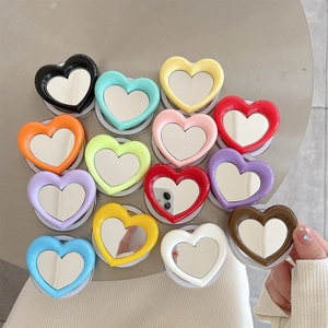 Flat lay of colorful heart-shaped phone grip mirrors on a grey surface in various vibrant tones