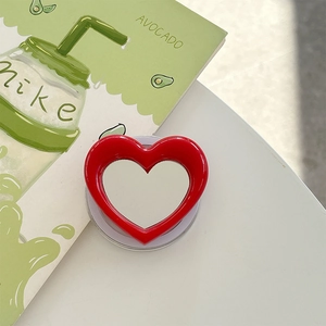 Macro detail of a red heart-shaped pop socket phone grip with a retractable base