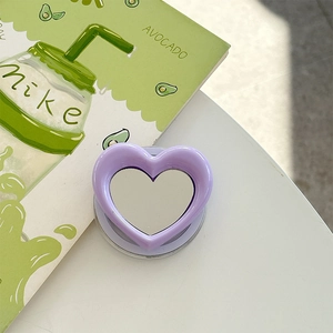 Detail of purple heart-shaped magnetic phone grip with a built-in makeup mirror on a white desk