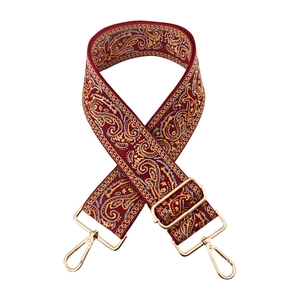 Close-up of red paisley embroidered bag strap with gold metal lobster clasps and buckles