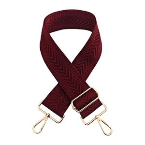 Macro detail of wine red chevron woven bag strap with polished gold metal swivel hooks