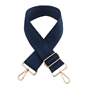 Detail of dark blue arrow pattern woven strap with gold metal lobster clasps for bags