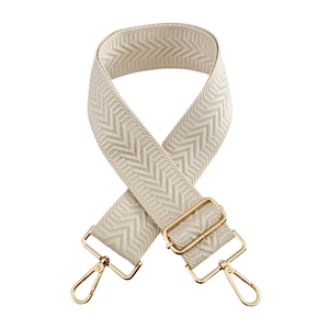 Detail of cream herringbone fabric bag strap with adjustable gold metal hardware buckles