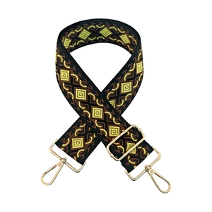 Close-up of diamond jacquard purse strap with gold metal hooks and geometric pattern