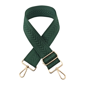 Detail of dark green woven crossbody bag strap with chevron pattern and gold metal hooks