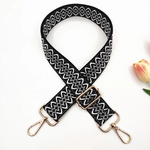 Macro view of adjustable woven bag strap with black white waves and gold metal hooks