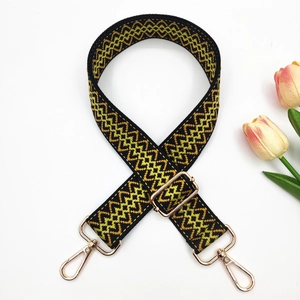 Close-up of bohemian woven wide shoulder strap with golden metal lobster clasps