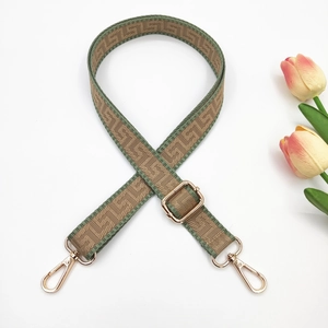 Adjustable woven strap with green geometric pattern and gold metal hooks on white background