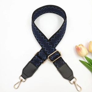 Detail of adjustable embroidered shoulder strap with blue geometric patterns and gold clips
