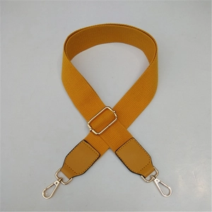 Detail of adjustable mustard yellow woven strap with gold metal buckle and leather ends