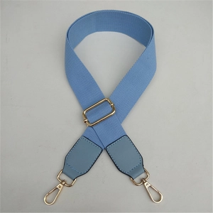 Détail de la bandoulière réglable en toile bleu clair avec des mousquetons en métal doré