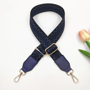 Detail of adjustable embroidered bag strap with floral jacquard and golden metal hooks