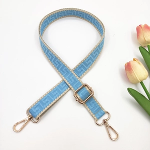 Detail of blue and beige geometric pattern bag strap with gold metal buckle