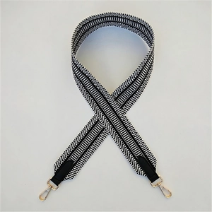 Detail of black and white geometric woven strap with gold metal hooks and leather ends
