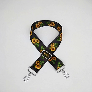 Detail of adjustable black bag strap with sunflower print and silver metal buckles