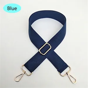 Detail of navy blue nylon bag strap with adjustable gold buckle and swivel hooks