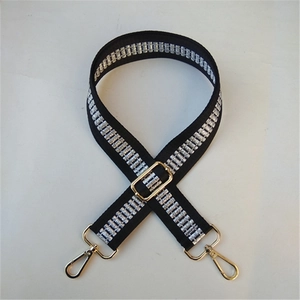 Close-up of adjustable wide shoulder strap with silver woven pattern and gold metal hooks