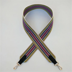 Detail of colorful geometric woven bag strap with black leather ends and gold metal clips